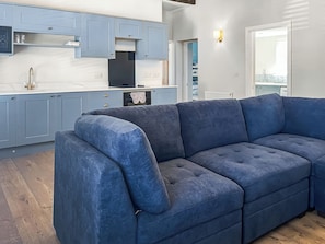 Eine moderne Küche mit blauen Schränken, einer weißen Arbeitsplatte und einem großen, blauen Ecksofa.