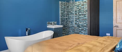 A modern bathroom with a freestanding bathtub, a glass shower enclosure, and a wooden wardrobe.