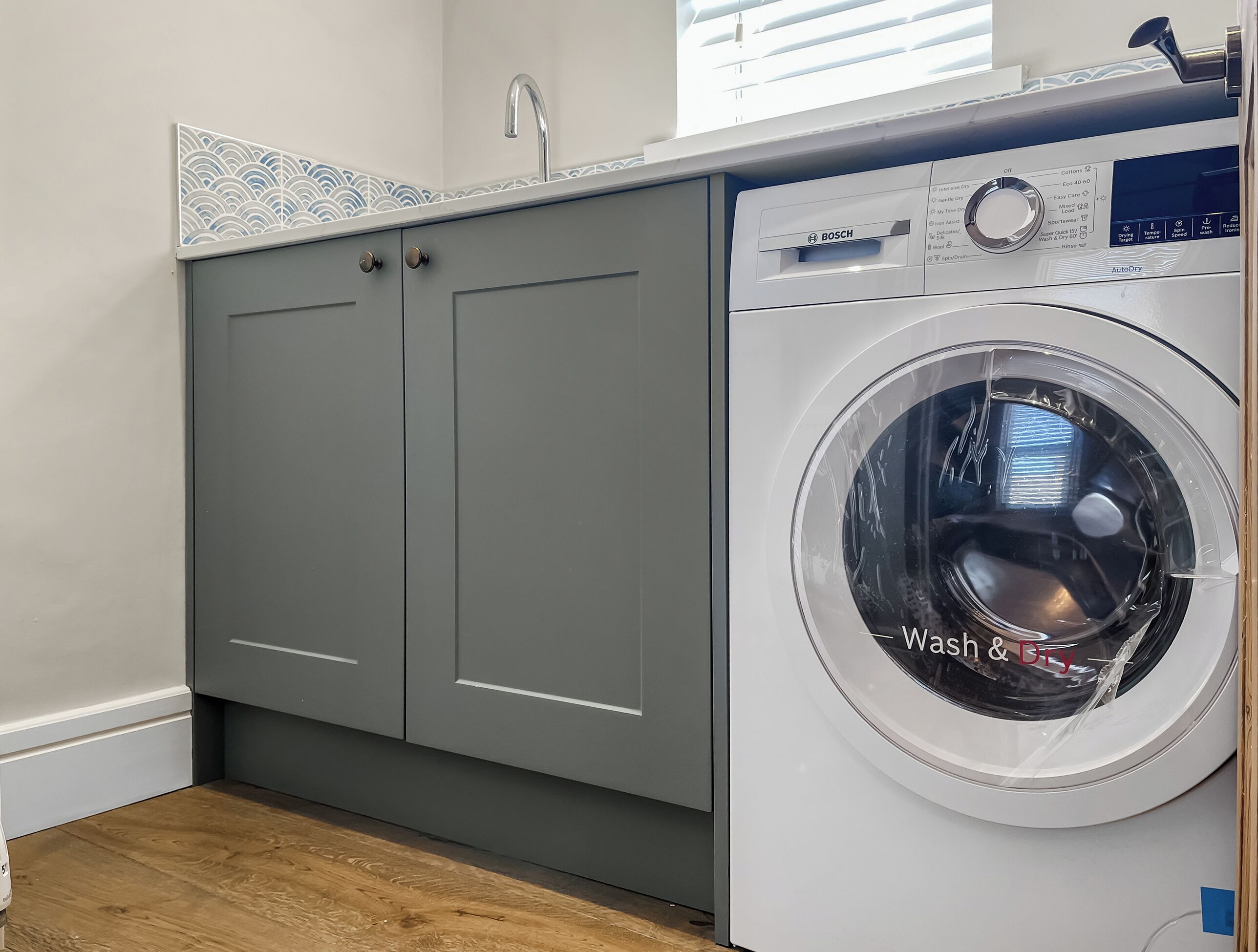 Un espace buanderie compact comprenant un lave-linge et des meubles de rangement gris.
