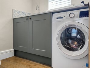 A compact laundry area with a washing machine and grey cabinets.