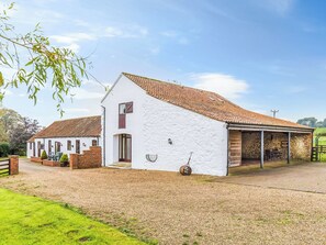 A white building with a tiled roof, a covered porch, and a gravel driveway. - The Barn Cottage - UK51885 (Grimblethorpe)