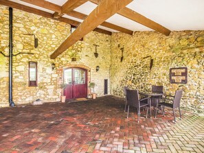 A stone-walled room with a wooden ceiling, a red door, and a brick floor. - The Barn Cottage - UK51885 (Grimblethorpe)