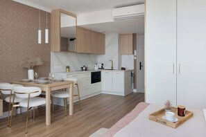 A modern kitchen with white cabinetry, a marble backsplash, and a dining area with a wooden table and white chairs.