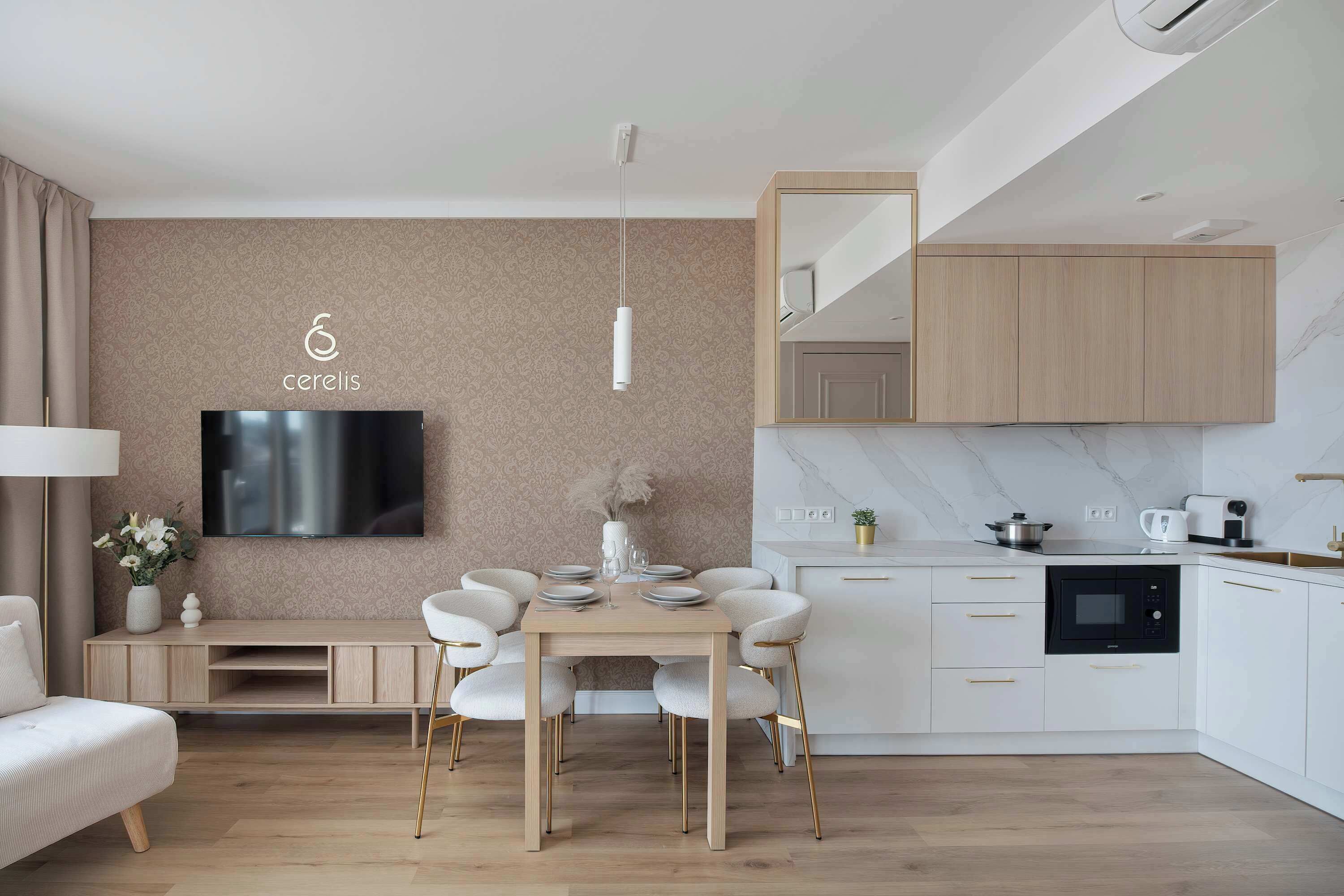Una sala moderna con televisor de pantalla plana, una mesa de comedor con sillas, un sofá y una cocina con armarios y electrodomésticos.