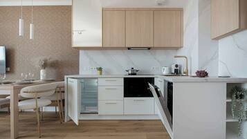 Una cocina moderna con horno empotrado, armarios blancos y un comedor con mesa y sillas.