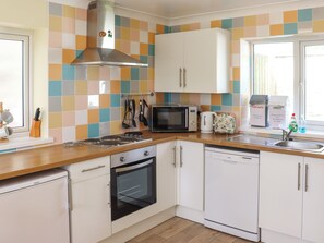 A kitchen with white cabinets, a microwave, a kettle, and a dishwasher. - 3 bedroom accommodation in Llandello (Llandello)