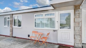 Un edificio con facciata bianca, un piccolo patio con tavolo e sedie, e una porta con una finestra sopra.