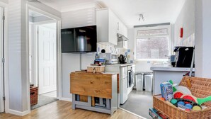 Una cucina moderna con TV, lavatrice e zona pranzo con tavolo in vetro e cesti in vimini.