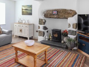 Ein Wohnzimmer mit Kamin aus Stein, einer Couch, einem Couchtisch und einem Fernseher.