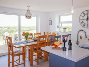 Eine moderne Küche mit Holzkästen, einem Esstisch, einem großen Fenster und Blick ins Grüne.