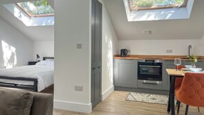Un apartamento moderno con habitación tipo loft, una cocina con zona de comedor y un tragaluz.