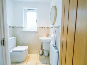 Ein kleines, sauberes Badezimmer mit Toilette, Waschbecken und Fenster.