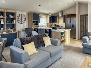 Una cocina moderna con una isla central, armarios empotrados y una zona de comedor con sillas.