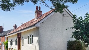Una casa a un piano con tetto a spiovente, un camino in mattoni e un muro esterno bianco.