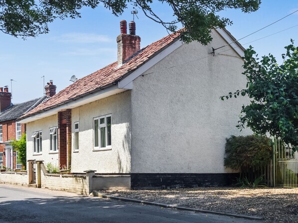 A single-story house with a pitched roof, a brick chimney, and a white exterior wall.