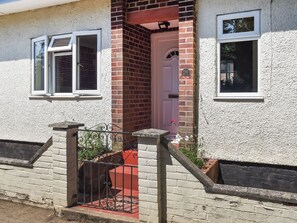 A house with a red door, a white window, and a brick wall.