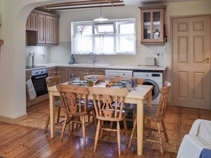 A kitchen with wooden cabinets, a dining table set for four, and a washing machine.
