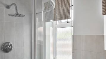 Een douche met een gebogen handdouche en een glazen deur.