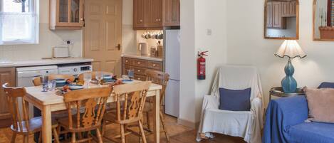 A cozy kitchen with wooden cabinets, a dining table with chairs, a sofa, and a lamp.