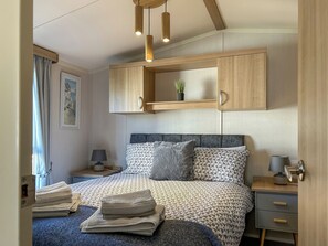 Ein Schlafzimmer mit Bett, Nachttischen, einer Wandlampe und einem an der Wand befestigten Regal mit Pflanze.