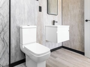 A modern bathroom with a toilet, a wall-mounted sink, and a mirror. - Swan Lake Lodge - UK51934 (Yarm)