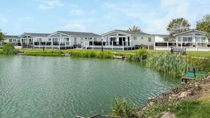 A row of mobile homes with a lake in the foreground. - Serenity at Lakeside - UK51947 (Patrington Haven)