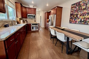 Una cucina moderna con mobili in legno, elettrodomestici in acciaio inossidabile e una zona pranzo con un tavolo lungo e sedie.
