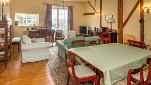 Una habitación acogedora con un piano, una mesa de comedor y televisión.