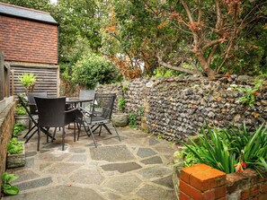 A patio with stone flooring, a table, chairs, and a stone wall. - Bay Cottage - UK51915 (Broadstairs)