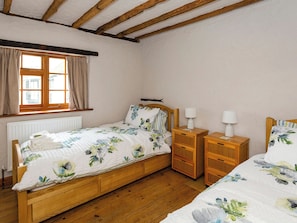 A bedroom with a wooden bed, two bedside tables, a window with curtains, and a radiator. - Bay Cottage - UK51915 (Broadstairs)