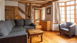 A cozy room with a wooden ceiling, a gray sofa, a leather armchair, and a wooden coffee table. - Bay Cottage - UK51915 (Broadstairs)
