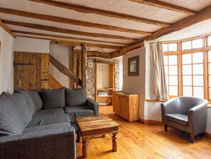 A cozy room with a wooden ceiling, a gray sofa, a leather armchair, and a wooden coffee table. - Bay Cottage - UK51915 (Broadstairs)