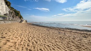 A sandy beach with a rocky cliff and a staircase leading up. - Bay Cottage - UK51915 (Broadstairs)