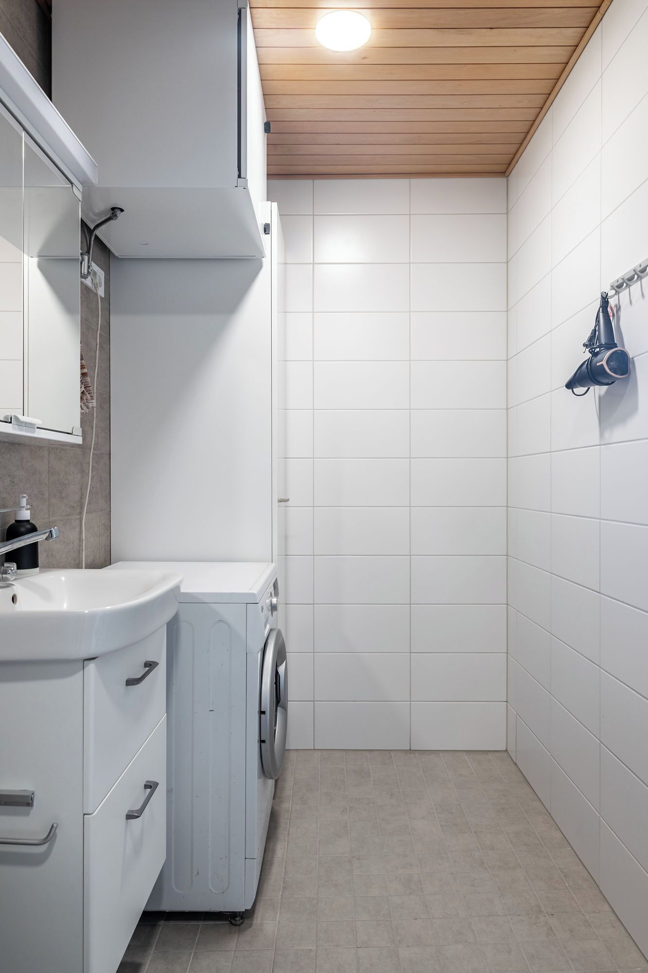 Un baño moderno y funcional con lavadora integrada, un lavamanos y un espejo.