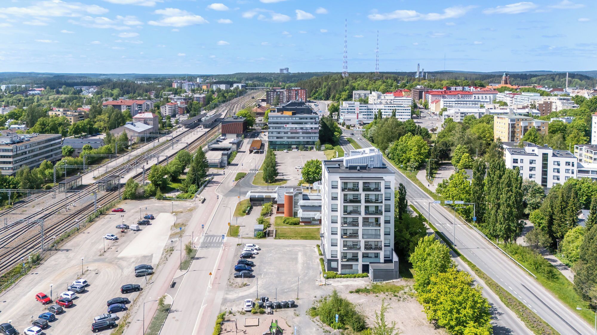 An urban area with modern buildings, a parking lot, and a railway station.