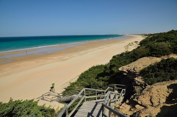 A beach with a wooden staircase leading down to the shore.