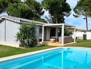 A residential property with a swimming pool, outdoor seating area, and a covered patio.