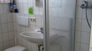Et badeværelse med toilet, håndvask og bruser.