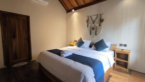 A bedroom with a wooden bed, a nightstand, a wall-mounted air conditioner, and a door. - Botanika Estate (Tetebatu)