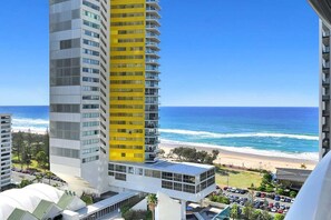 Ein Hochhaus-Hotel mit gelber Fassade, Blick auf den Strand und einem Parkplatz.