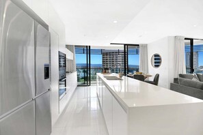 Eine moderne Küche mit einer großen Kochinsel, Edelstahlgeräten und Blick auf die Stadt.