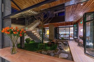 Un interior moderno con una escalera, un jardín pequeño y una zona de recepción.
