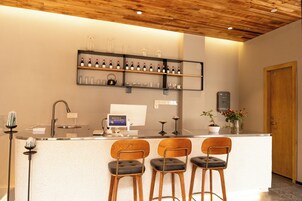 Uma área de bar com teto de madeira, um balcão com computador e três banquetas.