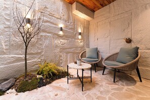 A stone-walled outdoor seating area with two wicker chairs, a small table, and a tree. - Luming Courtyard Hotel Xi'an City Wall (Xi'an)