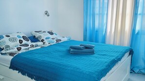 Une chambre à coucher avec un lit, une table de chevet, une lampe fixée au mur et un tableau.