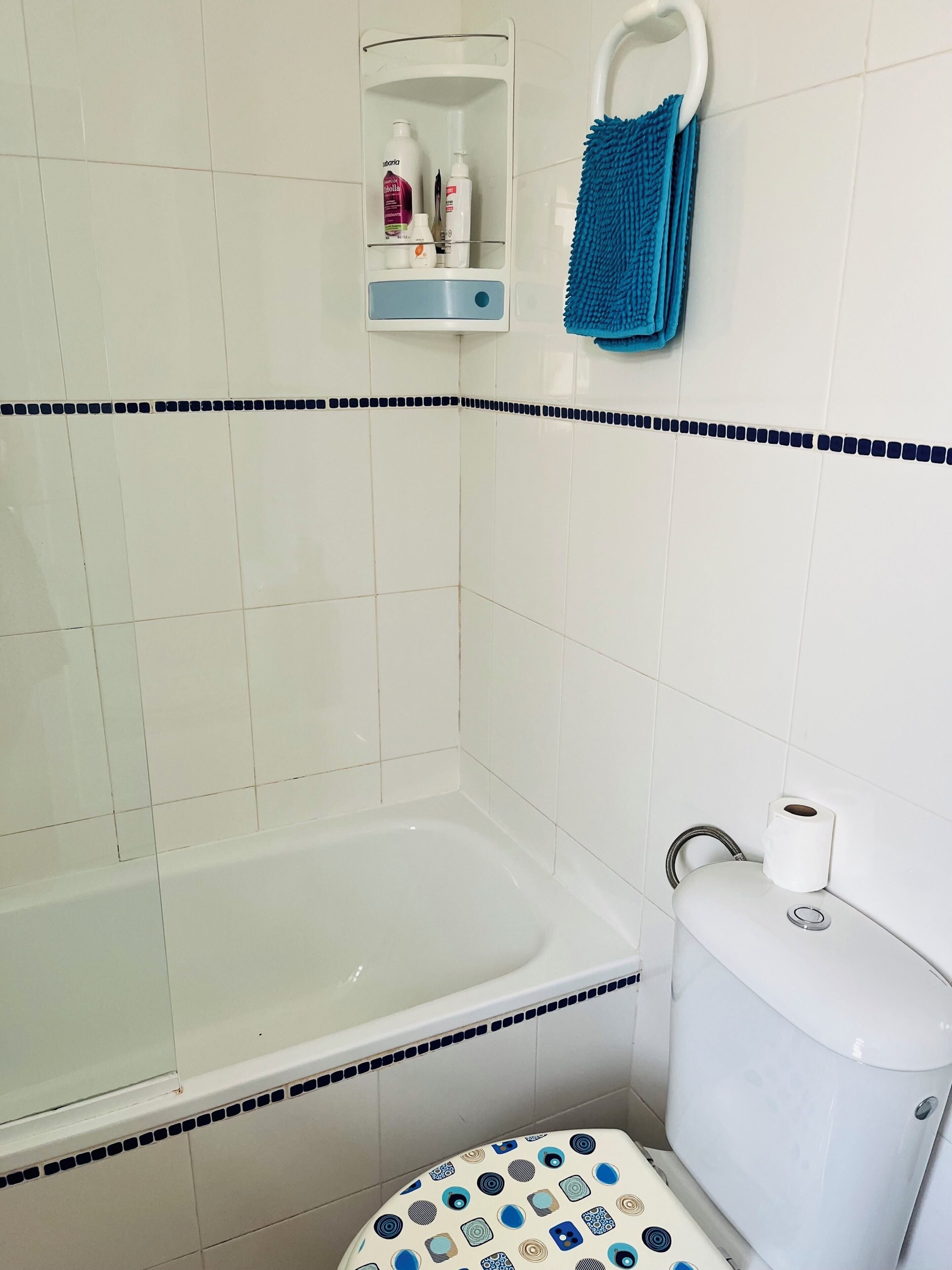 Ein Badezimmer mit Badewanne, Toilette und Ablage für Pflegeprodukte.