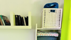 Une pièce bien rangée, avec des étagères remplies de livres, un petit phare jouet et un panier.