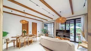 A modern living room with a sofa, dining table, chairs, and a TV. - Villa Sorento (Petulu)