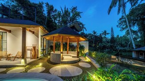 A modern outdoor lounge area with a circular seating arrangement, a pool, and surrounding greenery. - Villa Sorento (Petulu)