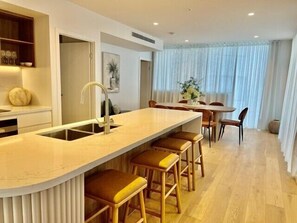 Eine moderne Küche mit Kochinsel, Barhocker und einem Essbereich mit Stühlen und Tisch.
